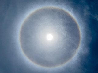Rainbow rings surround the sun, known as the halo sun phenomenon.