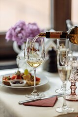 Waiter serving red wine in a fine dinning restaurant with happy female customer sitting at table