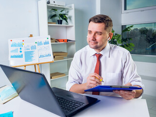 Smiling manager makes notes during online communication. New normal concept.