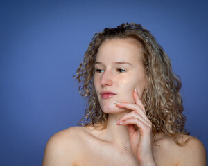 A girl with curly hair touches her chin, cosmetic patches to eliminate dark circles under the eyes