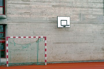 Cement wall with basketball board with hoop net and handball goal isolated on concrete background ...