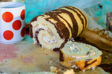 Cocoa roll with butter sliced on the table and a mug with red circles
