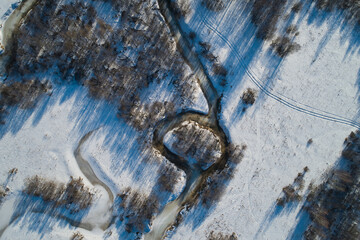 Beautiful Sunny landscape with forest, snow and frozen river. Aerial photography from a drone