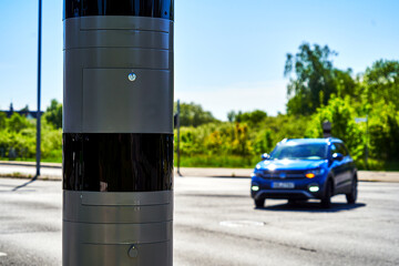 Stationary radar system measuring speed at an intersection in Germany where a blue car turns off