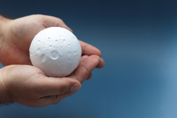 Man holds small figure of moon in two hands.