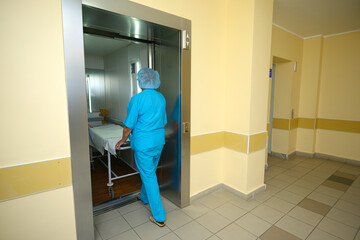 Nurse entering the elevator with a stretcher at the corridor of the hospital