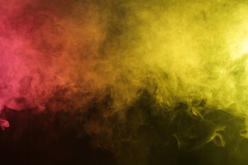Artificial magic smoke in red-yellow light on black background in darkness