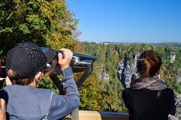 Children look through binoculars into the distance at the rocks and forest in the reserve