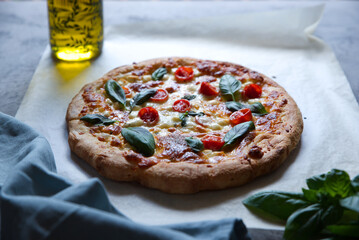 Homemade pizza with four types of cheeses, cherry tomatoes and basil.