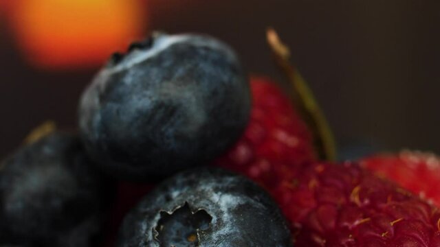 Delicious raspberry and blueberries against a sunset background