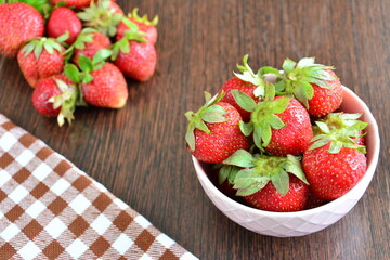 fresh strawberries in a pink bowl on the wooden background