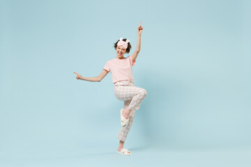 Fototapeta na wymiar Full length young overjoyed fun woman in pajamas jam sleep eye mask rest relaxing at home do winner gesture point finger up isolated on pastel blue background studio. Good mood night bedtime concept.