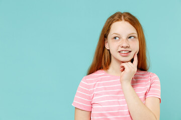 Little pensive dreamful thoughtful redhead kid girl 12-13 years old wearing pink striped tshirt prop up chin look aside isolated on pastel blue background studio. Children lifestyle childhood concept