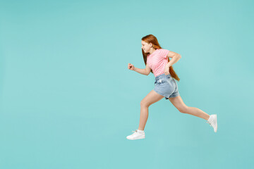 Fototapeta na wymiar Full length side view little overjoyed happy redhead kid girl 12-13 year old in pink striped t-shirt run fast hurrying isolated on pastel blue background studio Children lifestyle childhood concept.