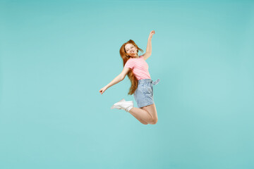 Full length little funny overjoyed happy redhead kid girl 12-13 year old in pink t-shirt with outstretched hands arms isolated on pastel blue background studio Children lifestyle childhood concept