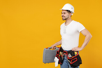 Young side view happy confident employee handyman man 20s in protective helmet hardhat tool case box isolated on yellow background Instrument accessories renovation apartment room Repair home concept