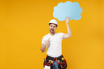 Young employee handyman man in protective helmet show blank Say cloud, speech bubble promotional content isolated on yellow background Instruments accessories renovation apartment room Repair concept.