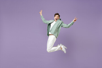 Fototapeta na wymiar Full length excited overjoyed amazed cool fun young man in casual mint shirt white t-shirt jump high with outstretched hands look camera isolated on purple violet background. People lifestyle concept