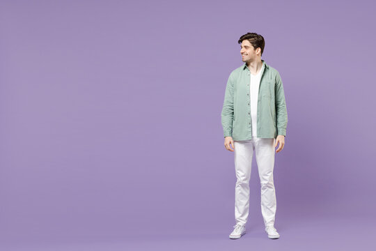 Full length fun smiling happy cool caucasian stylish man 20s wearing casual mint shirt white t-shirt standing look aside isolated on purple color background studio portrait People lifestyle concept