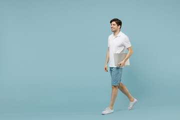 Full length young side view smiling fun man 20s wear white casual basic t-shirt hold closed laptop...