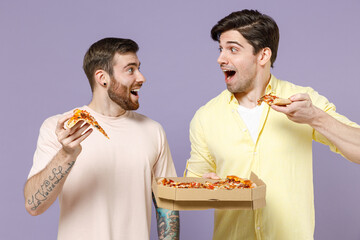 Two excited young men friends together in casual t-shirt tattoo translate fun eat italian pizza in...