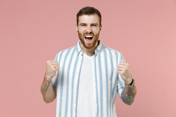 Young overjoyed happy excited successful caucasian unshaven man 20s in blue striped shirt white...