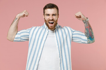 Young strong caucasian unshaven man 20s in blue striped shirt white t-shirt showing biceps muscles...