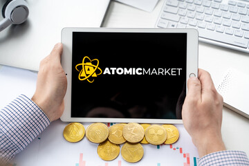 Russia Moscow 06.05.2021.Man holding tablet with logo of NFT marketplace Atomic market. Non fungible tokens for cryptocurrency WAX. Crypto coin for mining.Online game,gaming platforms
