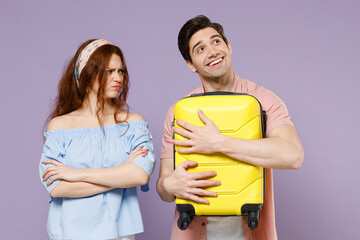 Fototapeta premium Two dreamful frowning offended traveler tourist woman man couple in shirt holding suitcase valise isolated on purple background. Passenger travel abroad weekends getaway Air flight journey concept