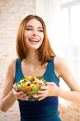 Portrait of happy amazed, smiling woman holding greece salad with cheese, indoor. Beautiful girl in casual blue dress - dieting, weight loss, healthy vegetarian eating concept.