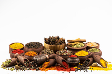 An assortment of oriental spices in wooden bowls isolated on a white background with space for text.