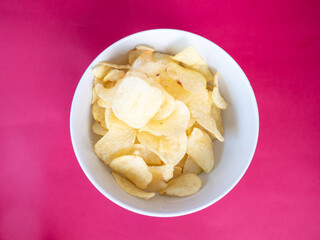 Potatoes chips in white bowl on red background