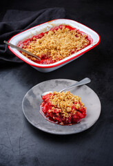 Modern style traditional American crumble cake with rhubarb and apple with backed topping served as close-up on a design plate and backing form