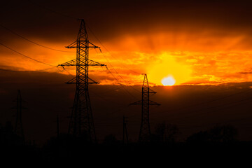 High voltage power line at sunset. Silhouettes of the metal pillars