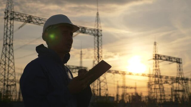 Senior electrical engineer working with tablet near electrical lines. Senior electrical engineer distributes electrical energy. Businessman electrician working with electrical energy with a tablet