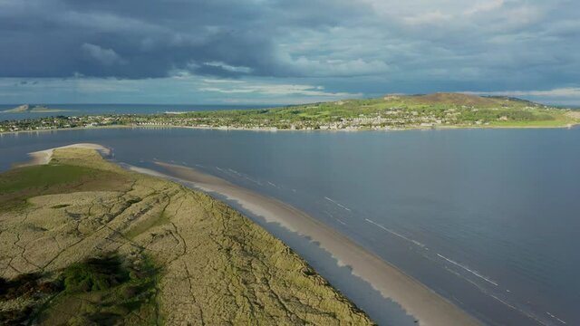 Aerial drone view over the textured landscape at North Bull Island revealing the Irish sea and Howth peninsula on the horizon.