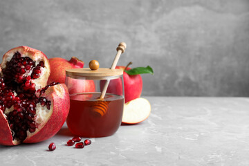 Honey, pomegranate and apples on grey marble table, space for text. Rosh Hashana holiday