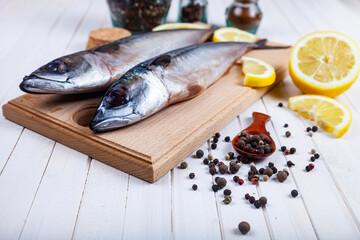 Raw mackerel on a cutting board with spices.