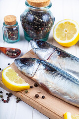 Raw mackerel on a cutting board with spices.
