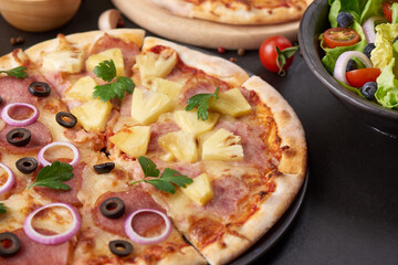 Italian pizza and pizza cooking ingredients on black concrete background. Tomatoes on vine, mozzarella, black olives, herbs and spices. Mixture pizza Italian food. Copy Space. Top view.