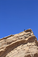 Young businessman standing on a huge rock 