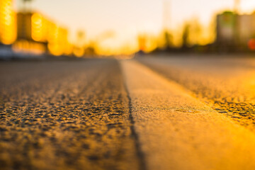 Sunny day in a city, asphalt lit by the rays of the setting sun. View from the level of the...