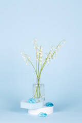 Intlation with lily of the valley flowers and geometric shapes on a blue background