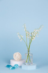Intlation with lily of the valley flowers and geometric shapes on a blue background