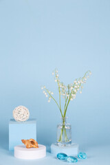 Intlation with lily of the valley flowers and geometric shapes on a blue background