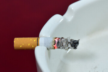 A smoldering cigarette butt on a porcelain ash tray.