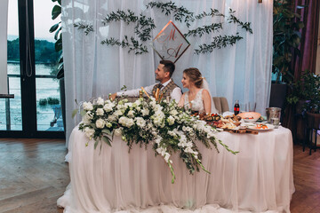 The bride and groom in the banquet hall are receiving congratulations. Newlyweds at the wedding table.