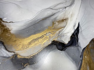 Abstract grey art with gold — black and whited background with beautiful smudges and stains made with alcohol ink and golden pigment. Gray fluid art texture resembles marble, watercolor or aquarelle.