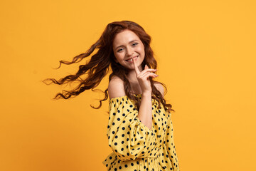 Laughing red-haired woman   having fun  in  yellow dress  with  sleeves over  yellow  background. Summer mood.