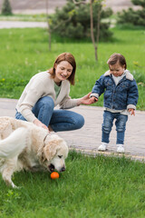 Obraz premium dog playing with ball near woman with autistic child